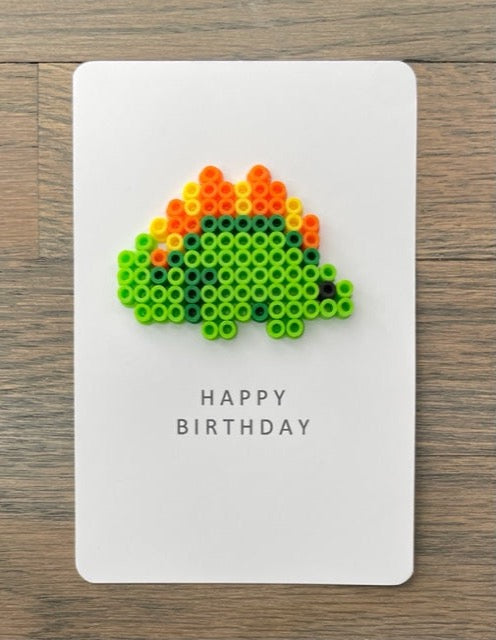 Picture of a Happy Birthday card with lime green, orange, and yellow dinosaur on it