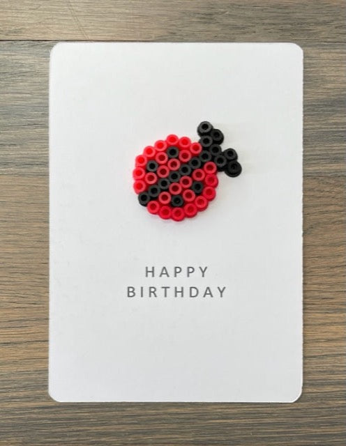 Picture of a Happy Birthday card with a red and black lady bug on it