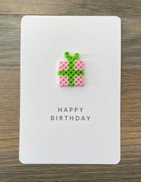 Picture of a Happy Birthday card that has a pink gift with a lime green ribbon on it