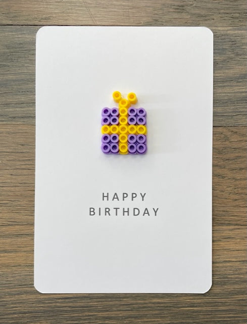 Picture of a Happy Birthday card that has a purple with yellow ribbon gift on it