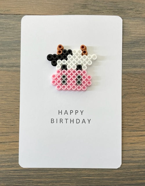 Picture of a Happy Birthday card that has a face of a black and white cow on it