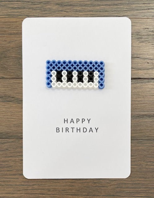 Picture of light blue keyboard with white and black keys on a Happy Birthday card.